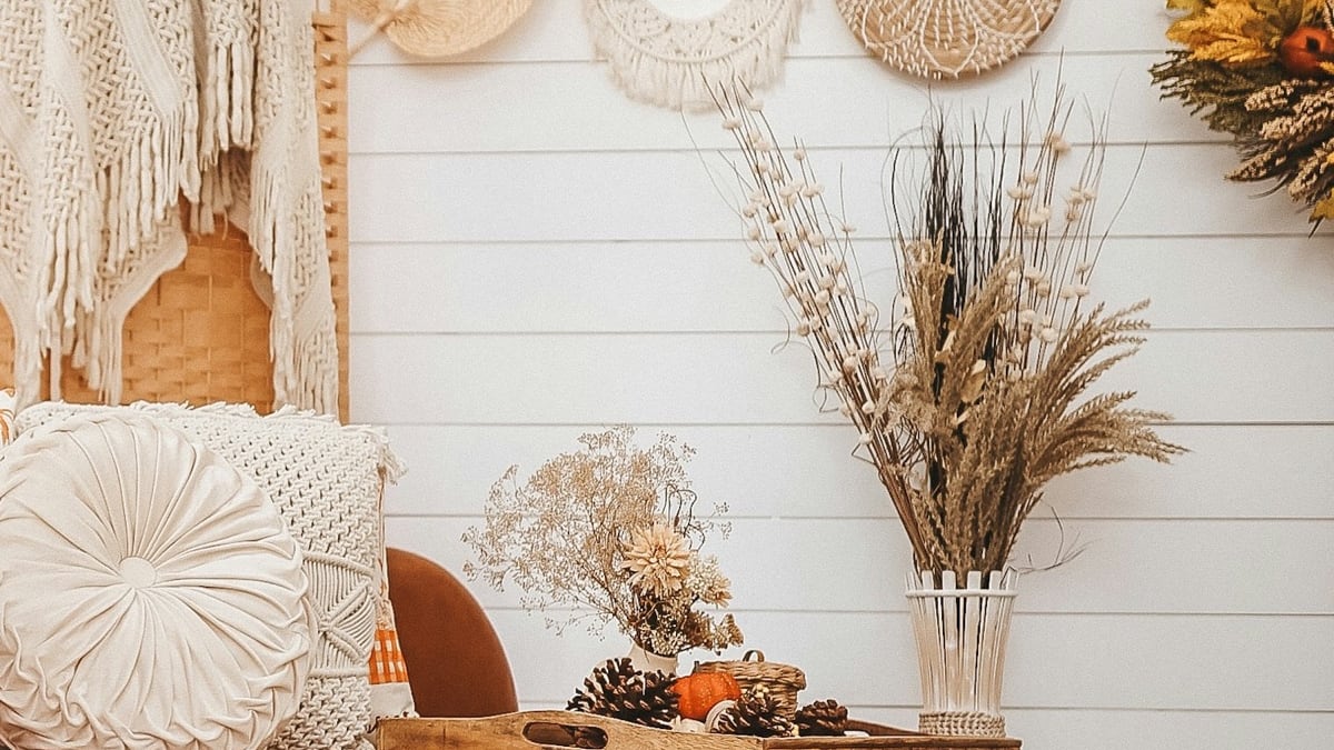 Cream pillows, dried florals, pinecones and small pumpkins arranged in a warm living room