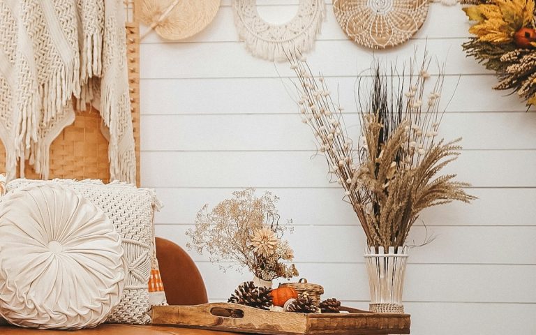 Cream pillows, dried florals and pumpkins arranged on a rust-colored living room sofa