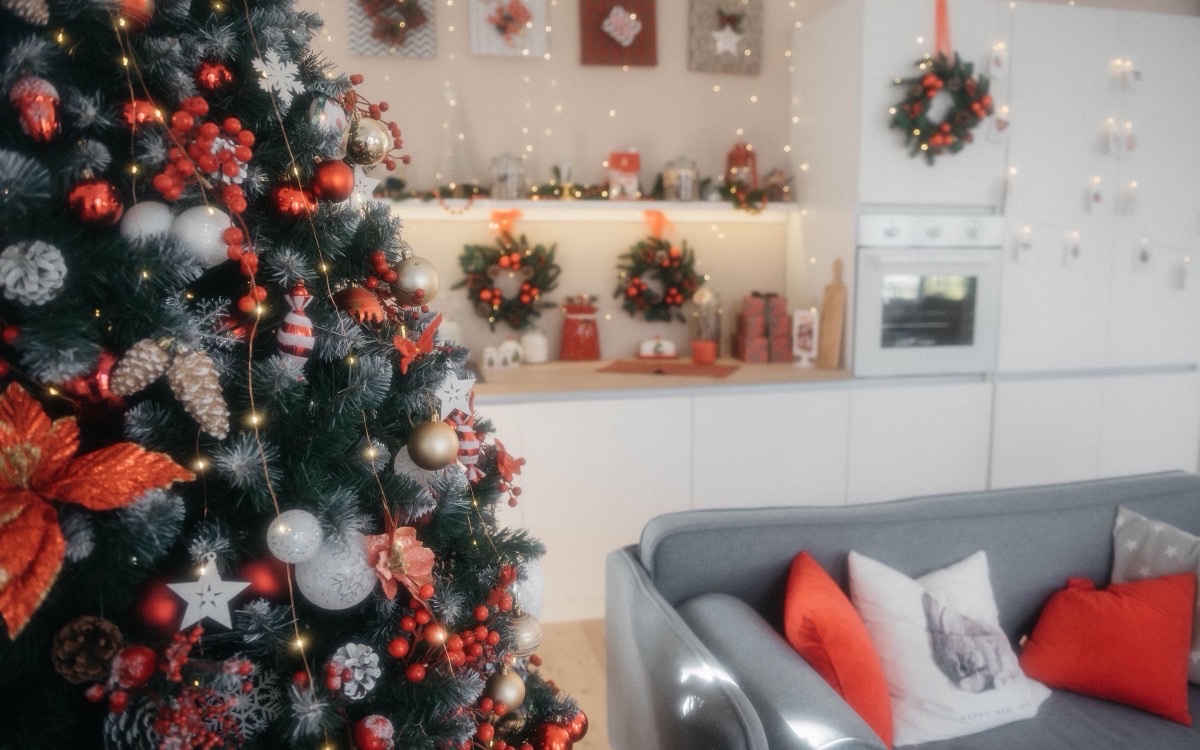 Warm white string lights on a red-and-gold Christmas tree in a bright living room