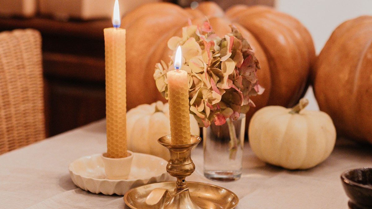 Pumpkins, taper candles and dried flowers arranged on a fall dining table