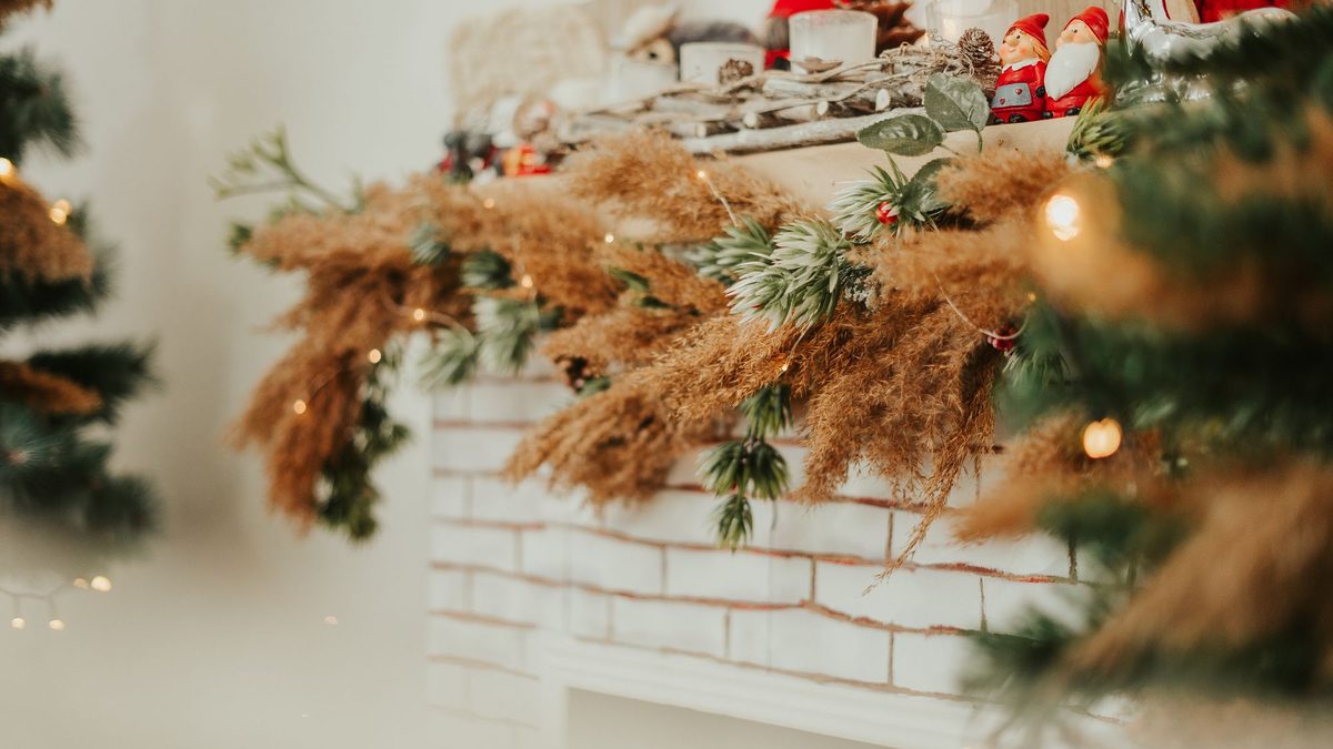 Evergreen garland and dried florals arranged along a white brick mantel