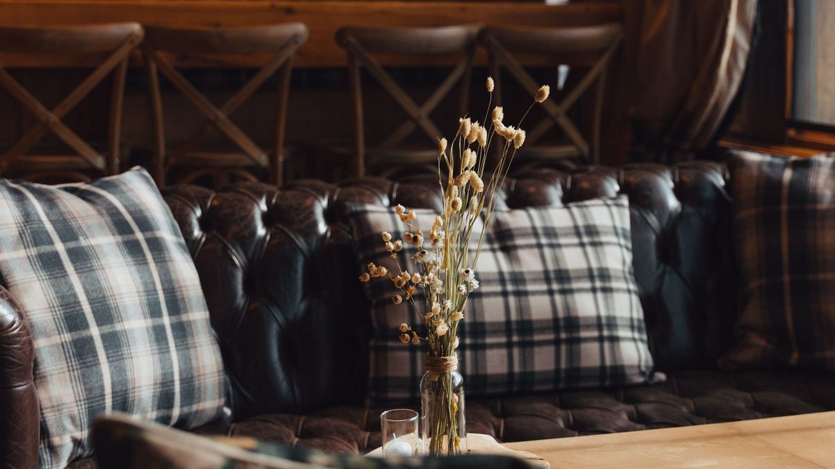Plaid pillows and dried stems layered on a rustic living room bench