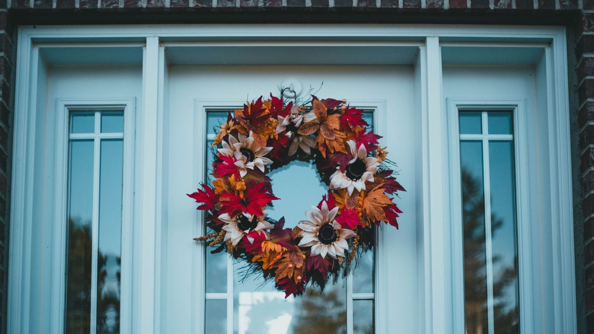 Red and yellow autumn leaf wreath on a pale blue front door