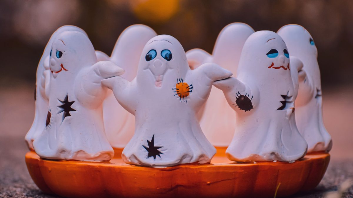 Small ceramic ghost figurines glowing on an orange tabletop