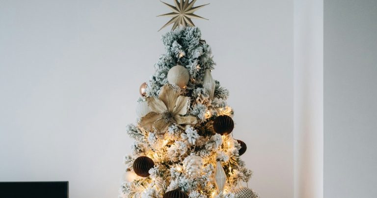 A flocked Christmas tree with warm lights and gold ornaments