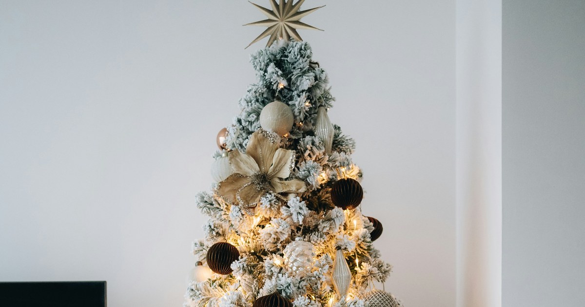 A flocked Christmas tree with warm lights and gold ornaments